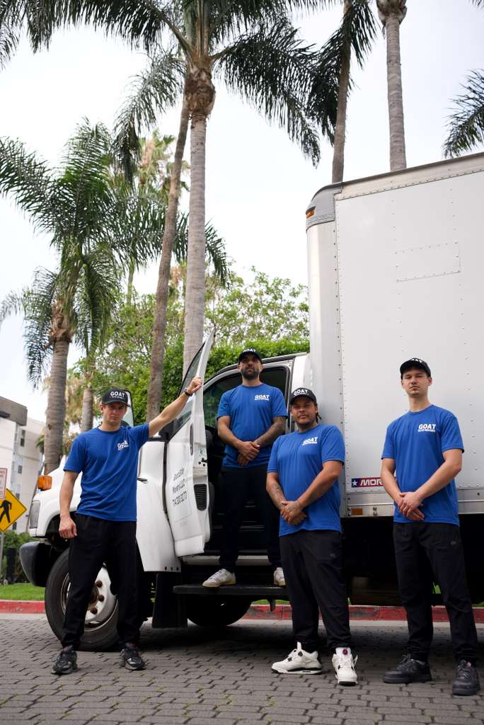 Four GOAT movers posing at the back of the truck